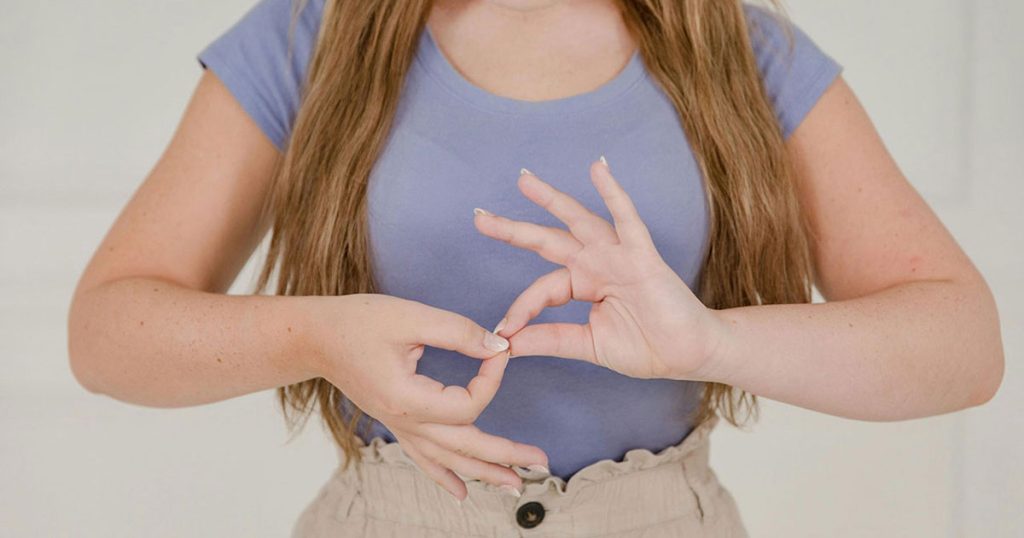 close up on womans hands while using sign language