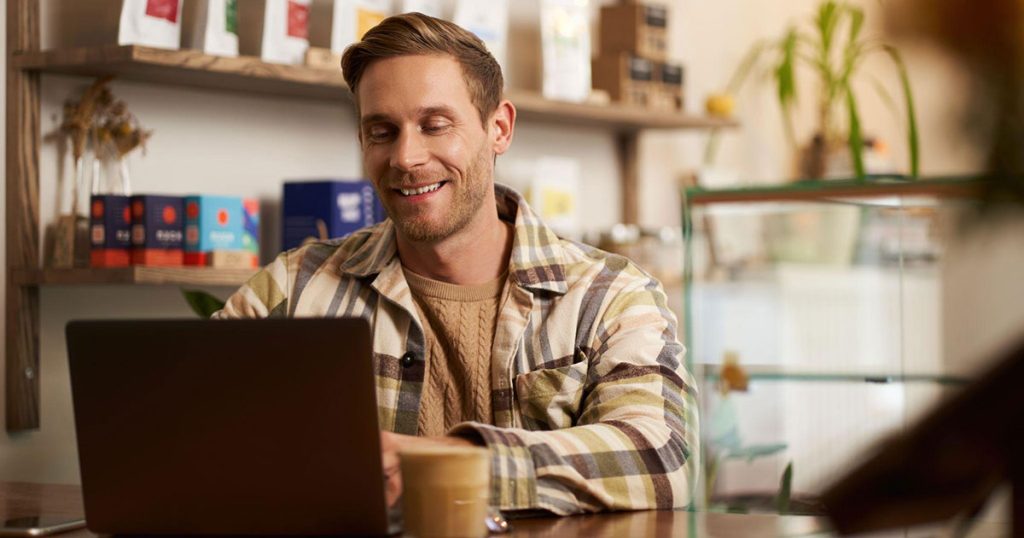Young man sitting at coffee shop with laptop